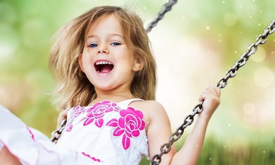 Little child blond girl having fun on a swing