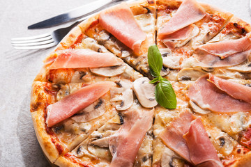 Hot pizza with prosciutto meat, tomato and mushrooms