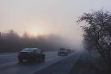 Fototapeta na wymiar Car traffic in fog with the rising sun