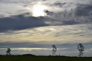Pôr-do-sol em paisagem rural, céu nublado