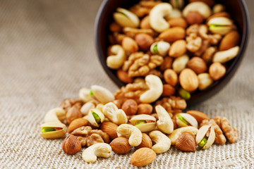Walnut platter spilled out of the cup on the background of cloth from burlap. Nuts as structure and background, macro.