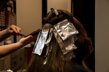 Closeup side view of hair foils during hair color and highlight process at a salon