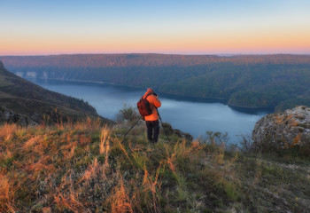 Fototapeta premium the photographer shoots the canyon of the picturesque river. tourist on the rock. autumn morning 