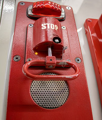 Red pull handle on wall. A emergency brake, close up. Fire alarm on platform at subway station.