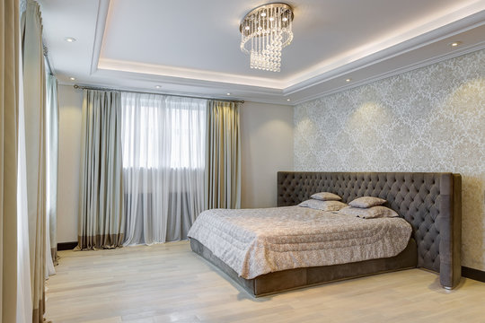 Interior of gray bedroom with crystal chandelier.