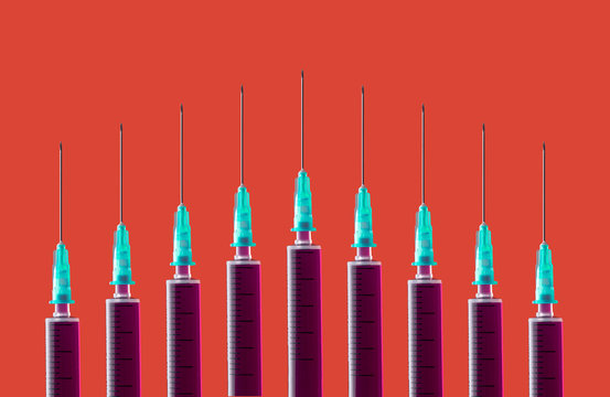 Multiple syringes organized in a pattern over orange background