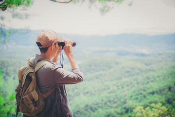 Young professional traveler man with binoculars, fantastic mountain landscape