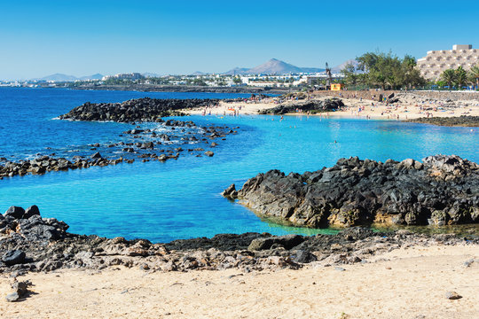 Lagoon with turquoise clear water in Playa Jablillo beach, in Costa Teguise, Lanzarote, Canary islands. Sandy beach with blue sea, volcanic rocks