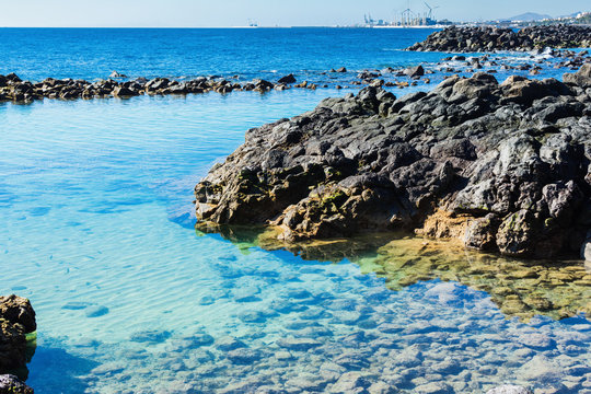 Lagoon with turquoise clear water in Playa Jablillo beach, in Costa Teguise, Lanzarote, Canary islands. Sandy beach with blue sea, volcanic rocks