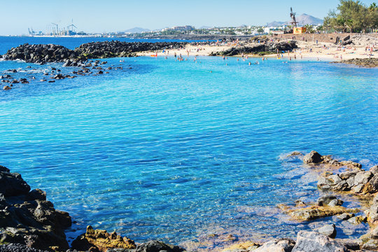 Lagoon with turquoise clear water in Playa Jablillo beach, in Costa Teguise, Lanzarote, Canary islands. Sandy beach with blue sea, volcanic rocks