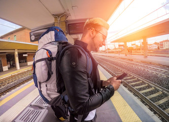 Traveler waiting for the train while checking his flight on his smartphone