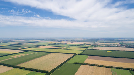 Naklejka premium Aerial view of fields with various types of agriculture, against cloudy sky