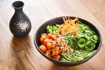 Poke bowl and sake on wooden background