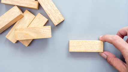 Arranging wood block stacking Business concept with hand on gray background