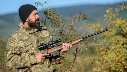 Bearded hunter spend leisure hunting. Hunting equipment for professionals. Hunting is brutal masculine hobby. Man aiming target nature background. Hunter hold rifle. Aiming skills. Hunting permit