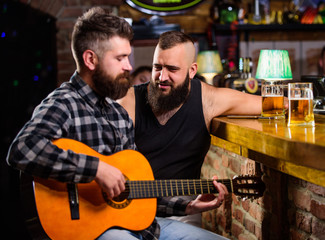 Friends relaxing in bar or pub. Real men leisure. Hipster brutal bearded spend leisure with friend in bar. Man play guitar in bar. Cheerful friends relax with guitar music. Friday relaxation in bar
