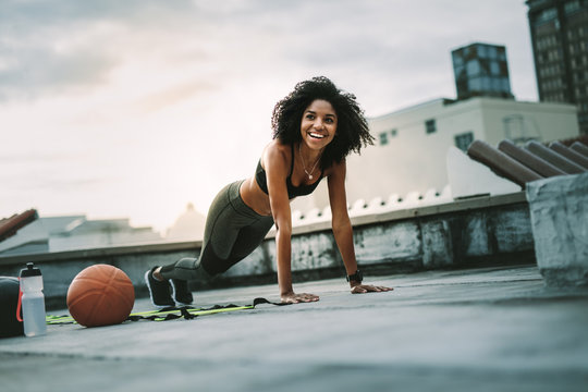 Fitness woman doing push ups on rooftop