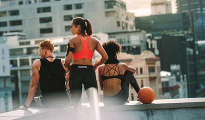 Rear view of athletic man and women sitting on rooftop © Jacob Lund