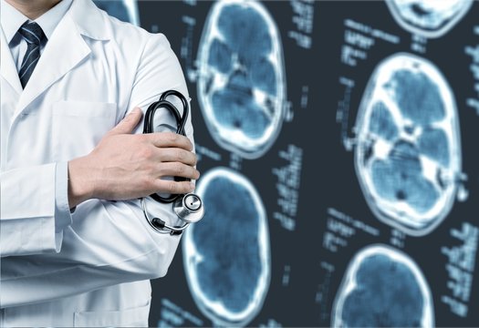 Doctor holding stethoscope standing near MRI Scanner images
