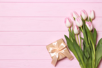 Fototapeta premium A bouquet of beautiful tulips and a gift on a wooden background top view. Mother's Day Background, International Women's Day. Holiday, give a gift.