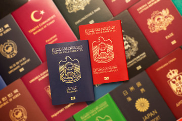 Blue and red biometric passports of United Arab Emirates on a blurred background of various documents of many countries of the world