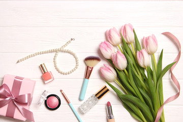 makeup products and beautiful spring flowers on wooden background. Top view.