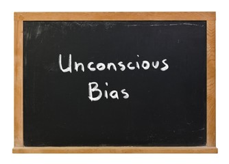 Unconscious Bias written in white chalk on a black chalkboard isolated on white