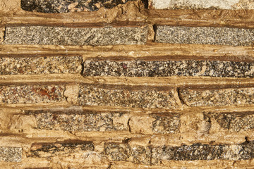 Fragment of a wall of small granite blocks. On the wall a thin layer of water flows. Background