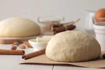 baking ingredients. dough closeup and butter, eggs, sugar, milk, cinnamon, almonds on a white wooden background