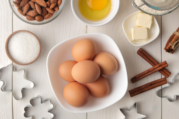baking ingredients. baking tools. butter, eggs, sugar, milk, cinnamon, almonds on a white wooden background. view from above