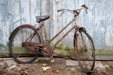 Verrostetes altes Fahrrad lehnt an einer Holzwand