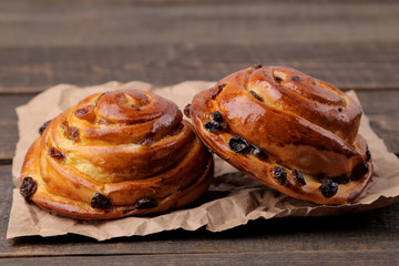 Tasty buns with raisins on a brown wooden background. fresh bakery. close-up.