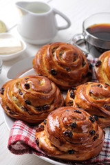 Tasty buns with raisins and coffee with milk on a white wooden background. fresh bakery. breakfast.