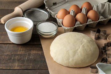 baking ingredients. baking tools. dough and butter, eggs, sugar, milk on a brown wooden background.