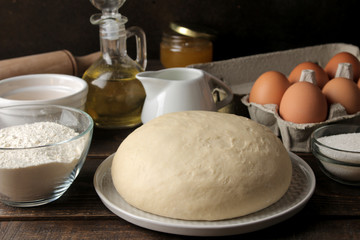 baking ingredients. baking tools. dough closeup and butter, eggs, sugar, milk on a brown wooden background.