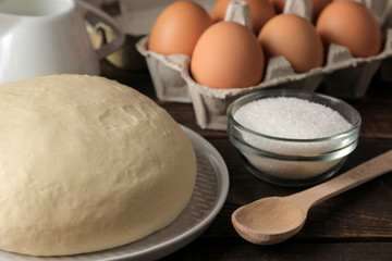 baking ingredients. baking tools. dough closeup and butter, eggs, sugar, milk on a brown wooden background.