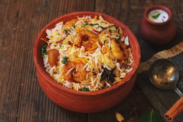 Prawn or Shrimp biryani in a clay poton wooden background, selective focus