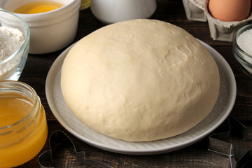 baking ingredients. baking tools. dough closeup and butter, eggs, sugar, milk on a brown wooden background.