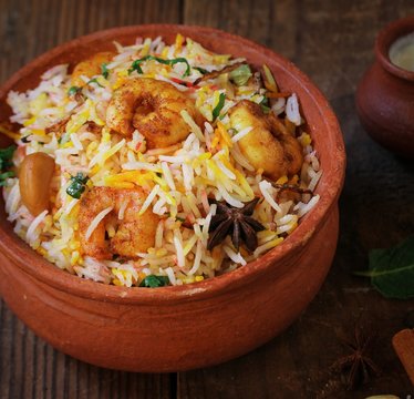 Prawn or Shrimp biryani in a clay poton wooden background, selective focus