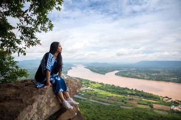 Naklejka premium Young woman sitting on a mountain top