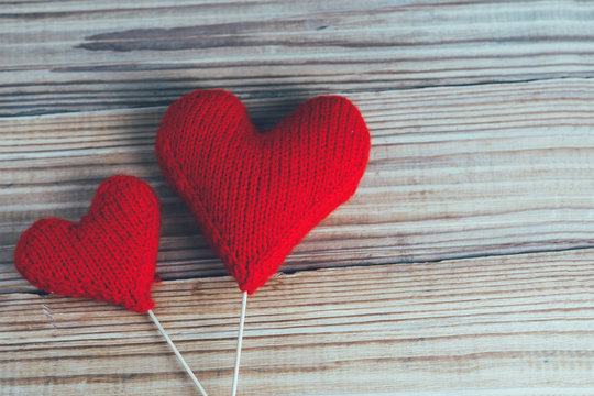 two red knitted hearts on wooden background . the concept of Valentine's day