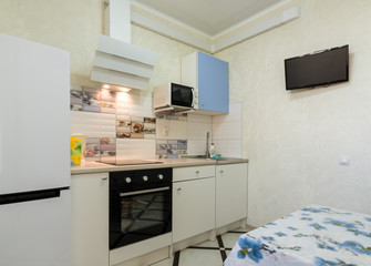 The interior of a small kitchen with a TV on the wall
