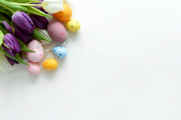Fototapeta na wymiar Tulips, Easter eggs on white wooden background. Flat lay. Top view.
