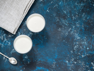Healthy breakfast. Yogurt in white glasses on a blue background. Top view, flat lay, copy space