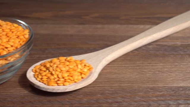 Lentejas naranjas crudas en un bol en la mesa de madera