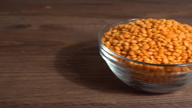 Lentejas naranjas crudas en un bol en la mesa de madera