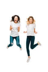 excited young women jumping and smiling at camera isolated on white