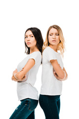 side view of upset young women standing back to back with crossed arms isolated on white