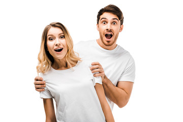 surprised young couple in white t-shirts looking at camera isolated on white