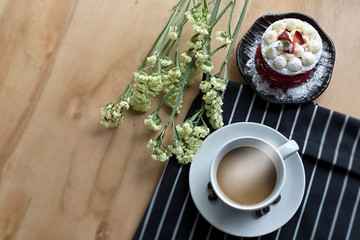 Cup of coffee and flowers on wooden table. Coffee on the table with candy placed. Top view with copy space.